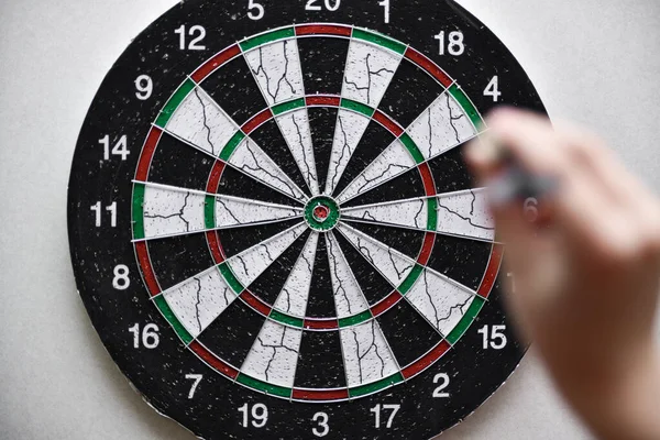 Dart board on the background of a hand with a dart.