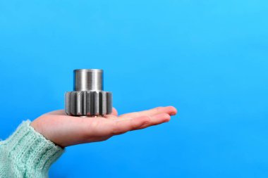 Kız avucunun içinde mavi bir arka planda vites kutusu tutuyor..