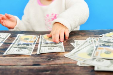 Küçük bir çocuk masanın üzerinde dolarları düzenliyor ve dikkatle onlara bakıyor..