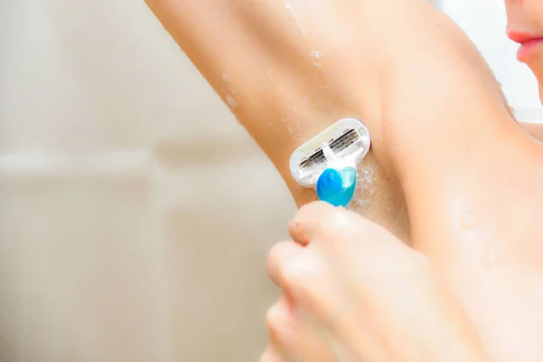 シャワーを浴びている女の子は剃刀機で脇の下を剃る 女性の衛生 介護用品 — ストック写真