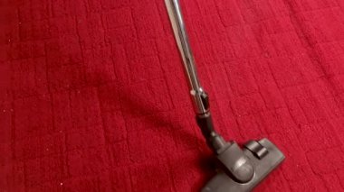 Bir ev kadını yerleri süpürür ve kırmızı zemindeki toz ve kiri temizler..