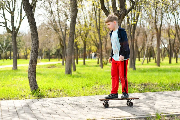 男孩在公园人行道上的一块滑板上滑倒了 — 图库照片