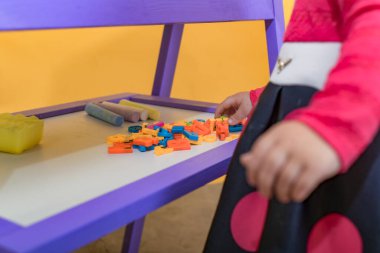 Küçük bir çocuk manyetik karttaki kelimeler için harfleri seçer. Çocuklar için anaokulu eğitimi kavramı.