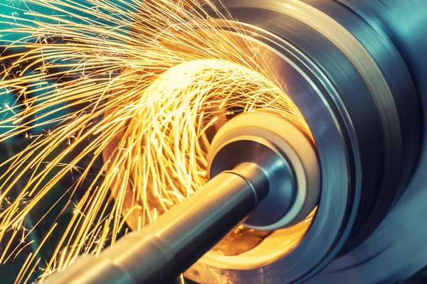 Silindirik bir parçanın iç gıcırtısı ve makinede aşındırıcı bir tekerlek var. Kıvılcımlar farklı yönlere uçuyor. Metal işleme.