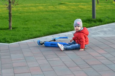 Küçük bir çocuk scooter 'dan düştü ve parka tırmanmaya çalışıyor..