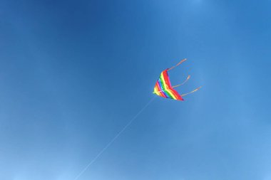 Mavi gökyüzüne doğru uçan renkli bir uçurtma.