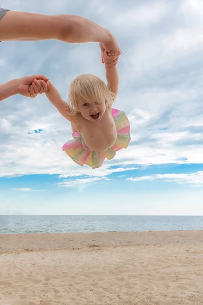 父は手で彼の娘を保持し 彼女を旋回 海岸で夏のゲーム — ストック写真