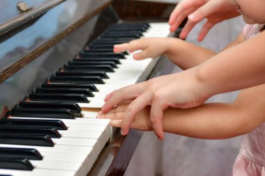 Öğretmen çocuğa piyanonun nasıl doğru çalınacağını gösterir. Müzik okulunda çocuklara öğretmenlik yapma kavramı..