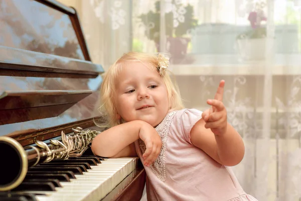 Uma Menina Alegre Está Apoiando Nas Teclas Piano Acenando Com — Fotografia de Stock