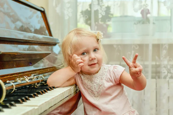 Egy Vidám Kislány Támaszkodik Zongorakulcsokra Integet Kezével — Stock Fotó