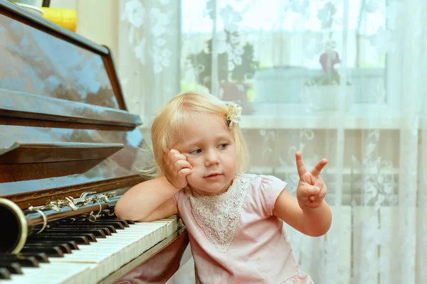 Egy Vidám Vidám Kislány Zongorakulcsokra Támaszkodik Két Ujjal Felfelé Mutat — Stock Fotó
