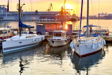 Yat kulübünde yelkenli teknelerle anakara akşam gökyüzü ve güneşli günbatımına karşı..