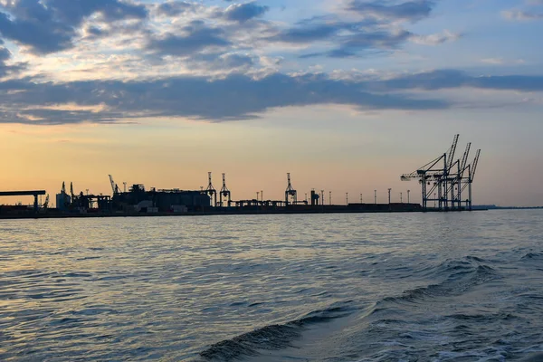 Cranes and industrial equipment in the sea, cargo port. View from the sea.
