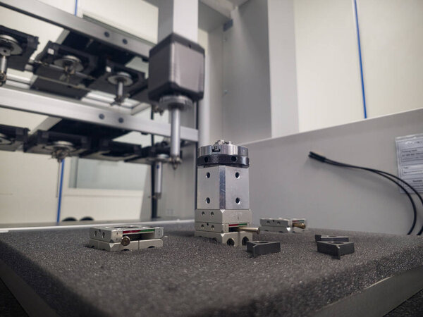 Close-up view of precision machinery parts arranged on a work surface in a well-lit workshop. Tools and components suggest active assembly by engineers focused on quality and accuracy.