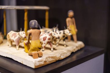 Çiftçi ve ineklerin oyulmuş ahşap figürleri, geleneksel kırsal yaşamı gözler önüne seriyor. Rakamlar düz bir yüzeye yerleştiriliyor ve günlük faaliyetleri kaydediyor..