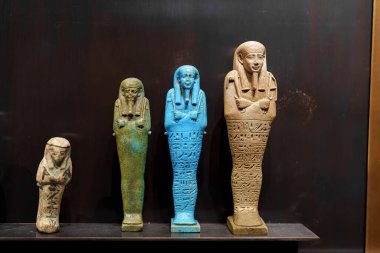 Dört eski Mısır heykeli bir müzede sergilenmektedir. Benzersiz tasarım ve ayrıntıları tasvir eden yeşil ve mavi gibi ayırt edici renkler sergiliyorlar. Yumuşak ışık eserleri çok güzel aydınlatıyor..
