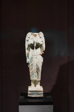 Kafasız antik bir heykel bir müze sergisinde duruyor. Taştan yapılmış, karmaşık detaylar ve sanat eserleri içeriyor, kültürel mirası ve önemi gözler önüne seriyor..