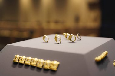 Çeşitli tasarımlardan oluşan altın yüzükler çağdaş bir kuyumcuda sanatsal bir şekilde sergilenir. Atmosfer lüks ve davetkar..