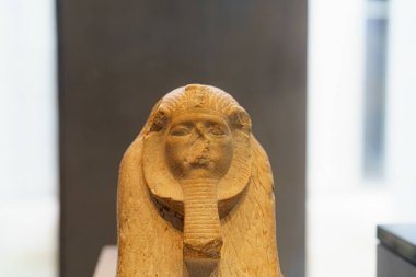 Antik Mısır kraliçesinin kafası. Karmaşık detaylar içeriyor. Parça müzede sergileniyor ve hafif ışıklandırma özelliklerini vurguluyor.