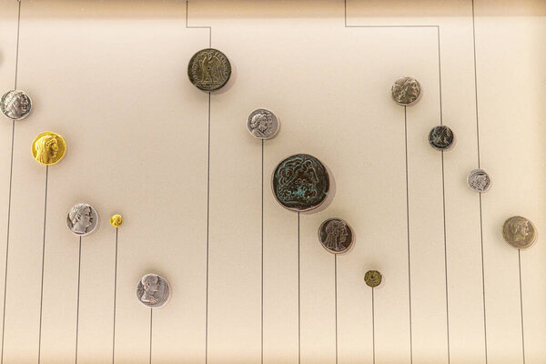 Коллекция исторических монет размещена на стенном дисплее, в котором представлены различные древние валюты разных культур. Экспозиция подчеркивает уникальные конструкции и материалы.