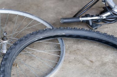 Bir bisiklet lastiği bir tekerleğin yanında ve bir bisiklet atölyesinde aletlerin yanında yatar. Dekor, onarım ve bakım için düzenlenmiş ve sergilenen ekipmanlarla dolu. Sahne, bisiklet servisi sırasında bir anı yakalıyor..