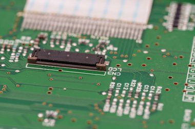 Detaylı görüntü yeşil bir devre kartı gösteriyor. Bağlayıcısı, rezistansları ve karmaşık bakır yolları görülebilir. Tahta karmaşıklık ve gelişmiş elektronik mühendislik öneriyor..