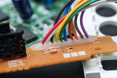 Elektronik devre kartının bir kısmına çeşitli renkli kablolar takılır. Diğer iç bileşenlerle birlikte, rezistanslar ve bağlantı noktaları tahtanın yüzeyinde görünür..