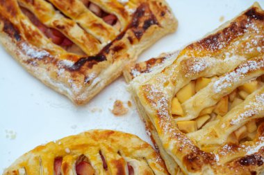 Beyaz bir yüzeyde üç altın-kahverengi elmalı turta düzenlenir. Pudra şekeri serpilmiş ve dilimlenmiş elmalarla dolu güzel kafes kenarları ile övünüyorlar..