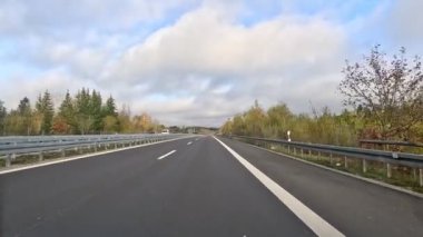 Sonbaharda otoban boyunca bir gezinti. Gökyüzü bulutlu ve yol Almanya 'nın manzarası boyunca uzanıyor. Sürücü koltuğundan bir manzara.