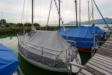 Yelkenliler, Almanya 'nın Bavyera şehrinde Starnberger' de bir ahşap iskelede dinleniyor. Tekneler, mevsimin sonunda ya da bulutlu bir gökyüzünün altında bir sonraki yolculuklarını bekleyerek korunuyor..