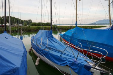 Starnberger See 'nin sakin sularına birkaç tekne yanaştı. Tüm tekneler parlak mavi muşambalarla kaplı, denizcilerin onları tekrar göle götürmesini bekliyorlar..