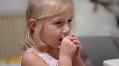 Oturan sevimli bir çocuk görülüyor. Dikkatlice açar, yer ve meyveli vitamin takviyesinin tadını çıkarır. Evdeki her ısırıkta keyif ve memnuniyeti ifade eder..