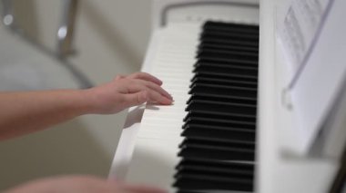Genç bir kişi onların konutunda piyano çalışır. Tuşların arasında hareket eden ellere, akorları ve melodiyi öğrenmeye odaklan. Bağlılık ve sanatsal gelişim üzerine bir çalışma.