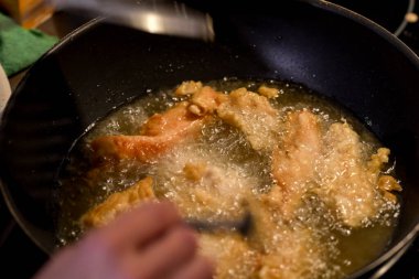 Ekmekli tavuk parçaları bir tava sıcak yağda cızırdıyor. Lezzetli ve çıtır çıtır bir yemek için bile karıştırılıyorlar..