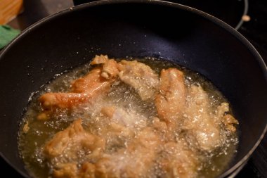 Tavuk parçaları büyük bir tavada yağda kızartılıyor, coşkuyla cızırdıyor, mutfakta nefis bir koku yaratıyor, servis edilmeye hazır..