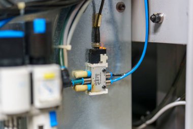 Kapaklar ve kablolar da dahil olmak üzere kontrol sistemi parçalarının yakın görüntüsü. Bu parçalar bir fabrikadaki otomatikleştirilmiş sistemin parçaları. Ayarlar yapılan işi gösteriyor.