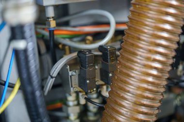 İki sensör mekanik bir düzenekteki boru ve kablolara bağlı. Yanlarında esnek bir hortum var. Bu kurulum endüstriyel ortamlarda yaygındır.