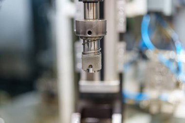 Bir makinede kullanılan hassas bir alete yakından bakmak. Bu araç, makine ve araçlarla dolu bir atölyede çeşitli parçalar üreten bir sistemin parçasıdır..