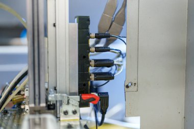 Equipment setup shows multiple connectors attached to a machine. Wires run from the connectors to the machine in a workshop during the day.