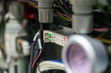 Bir atölyenin içindeki endüstriyel bir makinenin yeşil konnektörleri ve çeşitli kabloları. Makine, amacını ve işlevini vurgulayan birkaç parça ve detaya sahiptir..