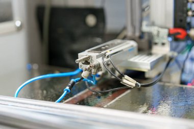 Bir mekanik çalıştırıcı bir fabrikadaki boru ve kablolara bağlıdır. Bu kurulum çeşitli ürünler için üretim bandında bir rol oynar. Çevre yoğun..