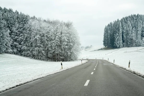 Sahne, karla kaplı, buzlu ağaçlar ve tepelerle kaplı dolambaçlı bir yolu gösteriyor. Kırsal kesimde sakin bir yerde sabahın erken saatleri..