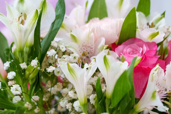 Kutlama için zambak, gül ve bebek nefesi içeren bir çiçek koleksiyonu bir bukette düzenlenir. Sahne, baharın canlı renklerini ve dokularını yakalıyor..