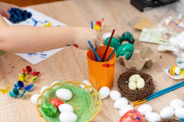 Çocuk resim yapmak için paskalya yumurtası boyuyor.