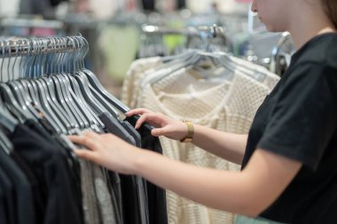 Kadın mağazadan yeni kıyafetler seçiyor..