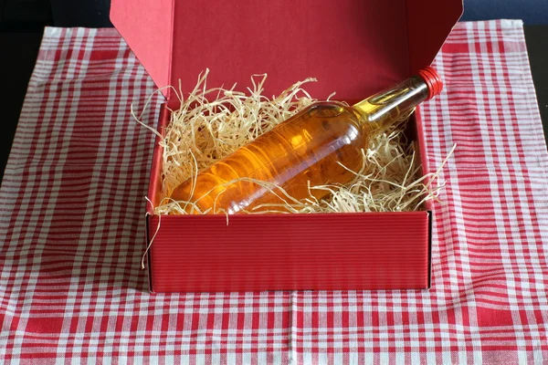 Caixa vermelha com palha e uma garrafa — Fotografia de Stock