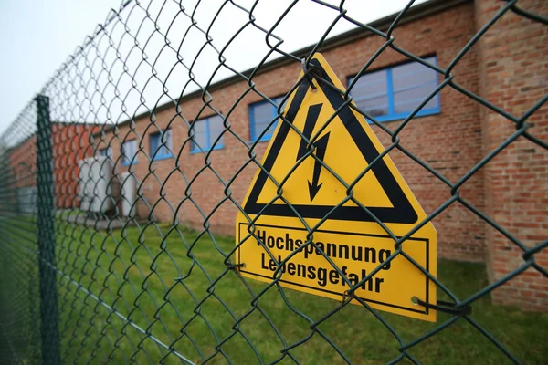 Segnale ad alta tensione su una recinzione in Germania — Foto Stock