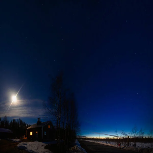 Moon and dusk at midnight over house in Swedish Lapland.