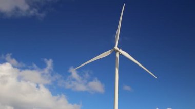 Mavi gökyüzü ve bulutları olan tek bir rüzgar türbini
