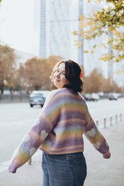 Sonbahar şehrinde rahat bir süveter giyerek yürüyen çekici bir kadın, kısa saçlı zarif bir bayan. Güneşli bir sonbahar gününün tadını çıkarıyorum..